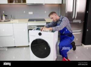 Technician repairing a washing machine in a modern Dubai home, showing professional home appliance repair and maintenance