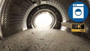 Homeowner inspecting the inside of a washing machine drum while checking for objects and mechanical issues in a clean laundry room