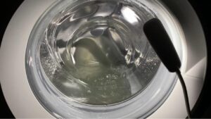 Realistic image of a washing machine highlighting causes of noise including unbalanced laundry, foreign objects, worn bearings, loose belts, clogged pump, and faulty shock absorbers.